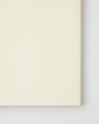 Cream blank notebook page close-up, edge and corner visible.