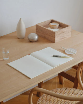 Open MD blank notebook on desk, cream pages visible, stitched spine.