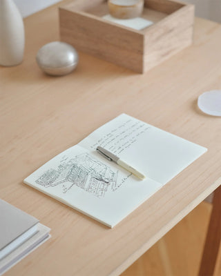 Blank cream notebook opened on desk with pen and line-art city sketch