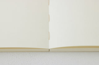 Thick notebook, open pages with central spine and blank beige sheets
