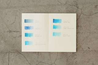Thick notebook spread with blue paint swatches and small printed labels