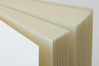 Thick cream notebook showing stacked pages along the side edge.