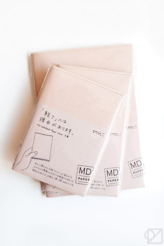 Stack of beige notebook paper covers with printed instructions and MD PAPER logo badge