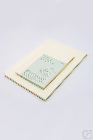 Cream graph paper pad with grid, showing a written sheet inside the cover.