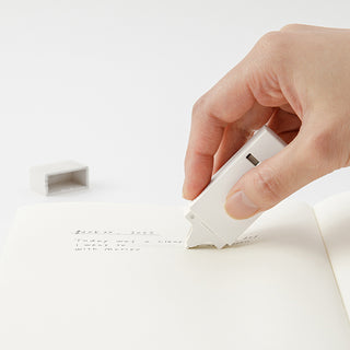 White 6mm correction tape dispenser being used by hand on paper