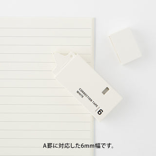 White 6mm correction tape dispenser resting on lined paper