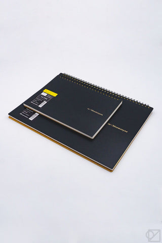 Grid spiral notebook, black cover partially opened to show white pages