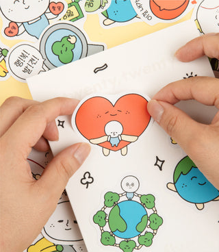 Orange heart character sticker being pressed onto a paper page with doodles