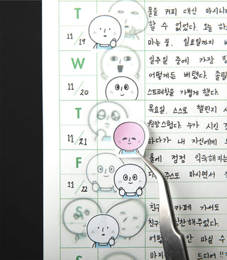 Close-up of a calendar-style sticker sheet with cute round character faces