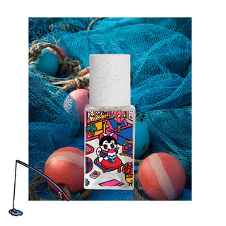 Eau de parfum bottle with colorful cartoon label, on blue mesh with stones
