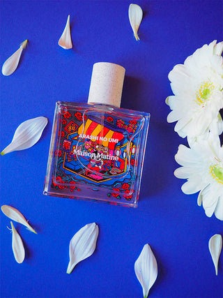 Eau de parfum bottle with cork-style cap and red-blue decorative label, centered