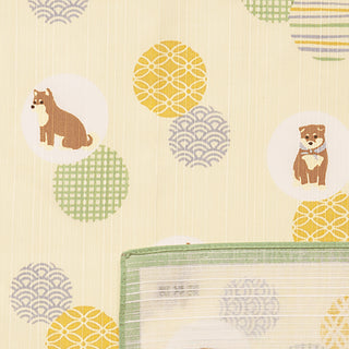 Furoshiki cloth in cream with shiba dog icons, citrus and wave motifs, and a green folded edge