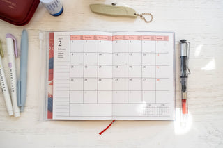 A6 weekly vertical planner refill open to a weekly calendar page with a red marker