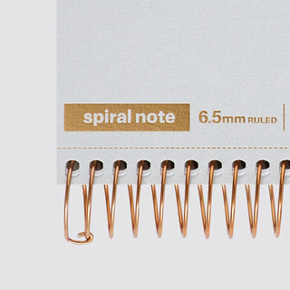 Close-up of copper spiral rings and label on 6.5mm ruled A5 notebook pages