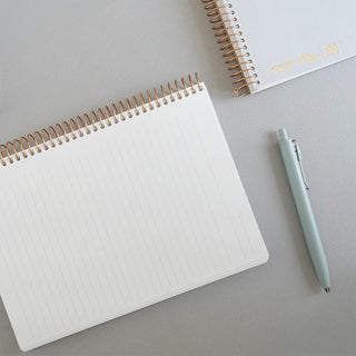 A5 spiral notebook with white ruled pages, copper rings along the top edge