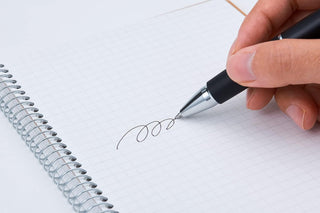 B5 spiral notebook grid page with black pen writing and blue grid lines