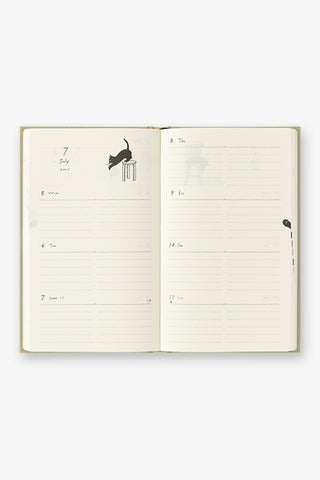 Open beige diary planner showing printed weekly/monthly grids and small cat icons