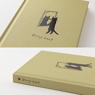 Beige diary planner close-up with black cat cover art on front and spine edge