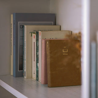 Stack of A6 two-page-a-day planners in blue and brown covers