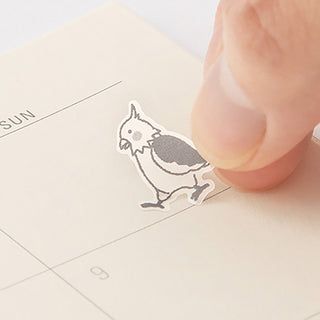 Small outline cat sticker being pressed onto a planner page