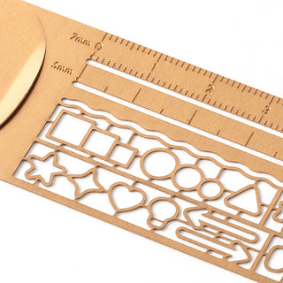 Copper clip ruler close-up with decorative stencil cutouts and mm measurement marks