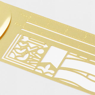 Close-up of gold clip ruler showing white ornate pattern and measurement guide lines
