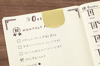 Gold clip ruler holding a planner page with decorative border and markings