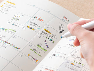 Hand using rotary cat stamp on printed calendar grid