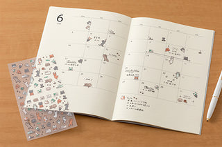 Cat planner sticker sheet beside an open monthly planner page with small icons