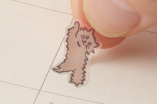 Single cartoon cat sticker with pink outline being applied by a finger