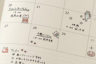 Monthly planner calendar page with small cat sticker icons on dates