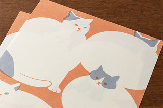 Close-up of white and blue cat illustrations on orange stationery paper