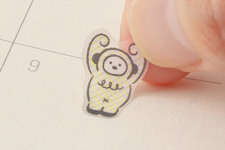 Small monster sticker being placed, featuring a bear-face in a striped outfit