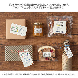 Stationery on a wooden table with forest animal date stamp labels and thank-you tags