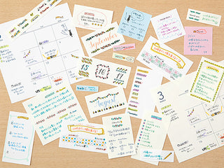 Assorted stamped paper labels and memo cards with colorful decorative motifs scattered.