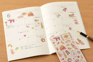 Open planner with Thai-themed sticker sheet showing colorful icons and numbers