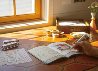 B6 dot grid notebook open on a table, travel illustration pages and writing space