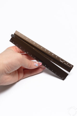 Brown aluminum multi ruler with dual measurement scales and round pivot fastener