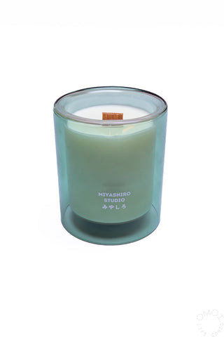 Green glass jar candle with wood wick, white wax, and Miyashiro Studio branding.