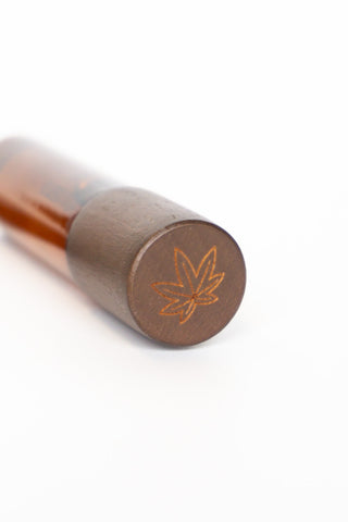 Dark brown cap end with leaf logo on amber roller skin scent bottle