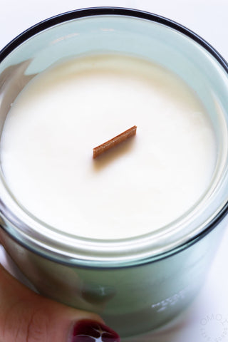 Top view of green glass jar candle with wood wick in white wax.