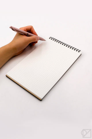 A5 spiral memo notebook open to white grid pages, metal spiral binding