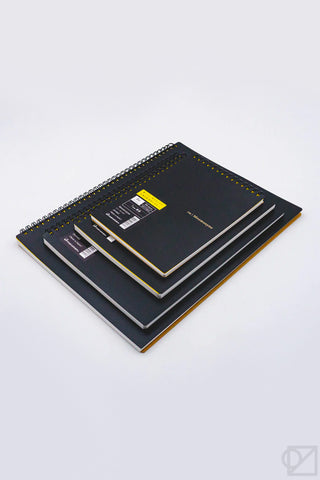 Stack of black spiral lined notebooks with yellow-edged covers and visible rings.