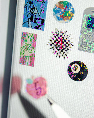 Assorted holographic-style stickers on white sheet: hearts, starbursts, icons