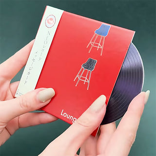 Red 'Lounge' record message card with stool illustrations, held over a purple vinyl disc