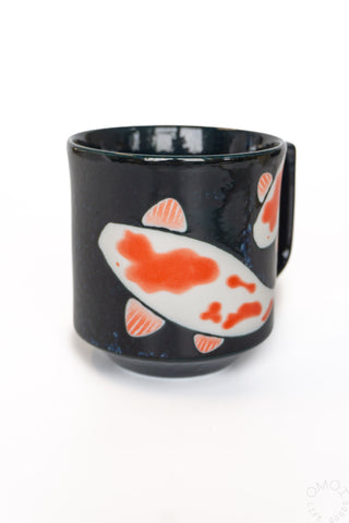 Black ceramic mug with orange koi fish and fins, front view