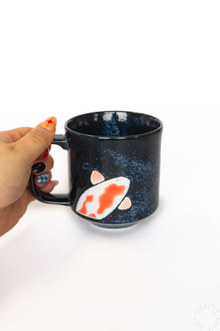 Black ceramic mug with koi fish print and handle, blue speckled glaze