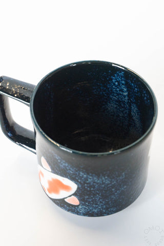 Black speckled ceramic mug interior and rim, koi design on side