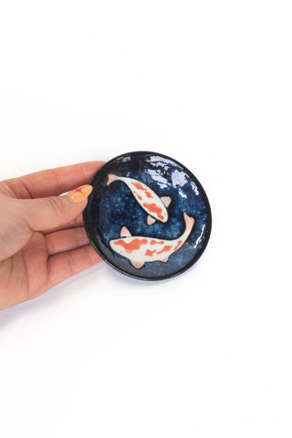 Dark blue koi sauce dish held in hand, glossy round bowl with fish artwork
