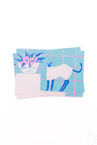Light blue postcard with white cat, blue grid lines, and pink flower illustration